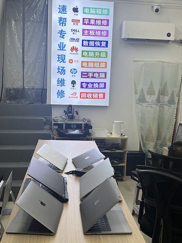 门店长桌陈列多台待检笔记本与墙面服务灯箱