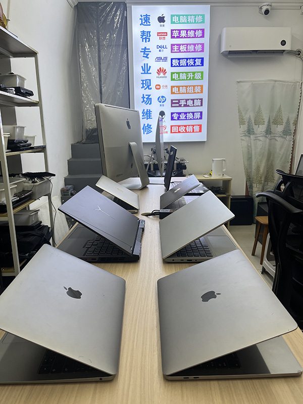 店内木纹长桌整齐陈列的银色笔记本与一体机